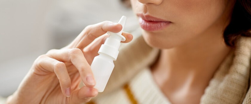 Kobieta aplikuje sobie lek przez aerozol do nosa