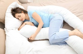 kobieta w ciąży śpi ze specjalną poduszką