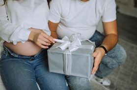 Para spodziewająca się dziecka otwiera prezent. Co kupić na prezent przyszłym rodzicom?