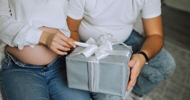 Para spodziewająca się dziecka otwiera prezent. Co kupić na prezent przyszłym rodzicom?