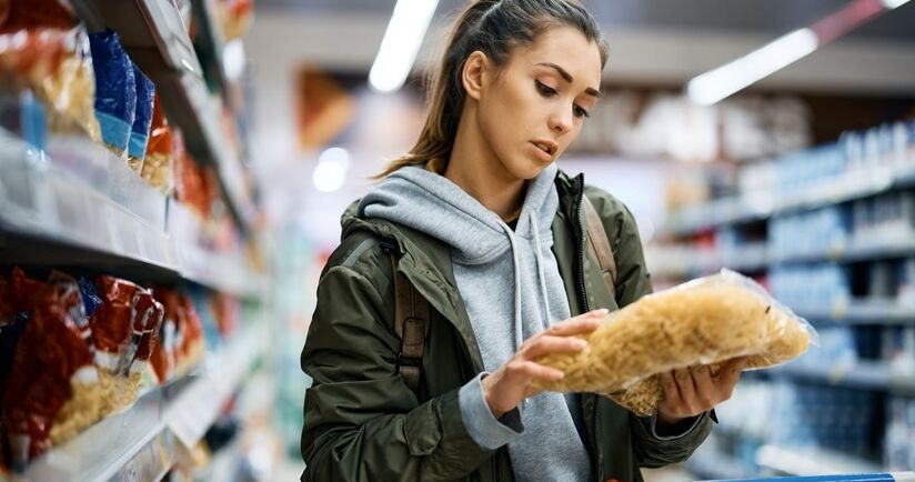Młoda kobieta czytająca etykietę produktu. Dodatki do żywności, lista e, e w żywności, składniki e, dodatki e.