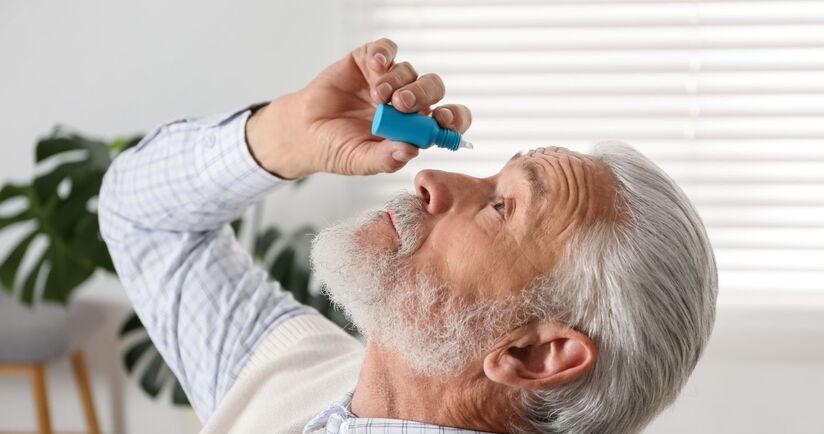 Mężczyzna z alergicznym zapaleniem spojówek zakrapla sobie oczy. zapalenie spojówek na tle alergicznym, alergiczne zapalenie spojówek objawy, co na alergiczne zapalenie spojówek